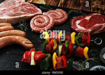 Un assortiment de délicieux crus de viande avec légumes sur un barbecue avec t-bone steaks, saucisses et brochettes de viande et le poivre Banque D'Images