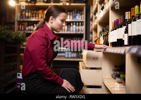 Photo sur le côté de la jeune brunette vendeur en magasin en contexte de racks Banque D'Images