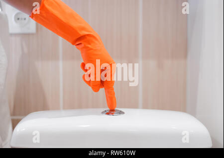 Le doigt de femme appuyant sur le bouton et le rinçage toilettes Banque D'Images