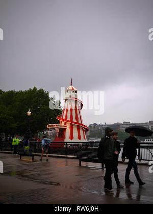 Un rouge lumineux et blanc contraste helter skelter contre les toits de Londres Londres gris sur la rive sud. Banque D'Images