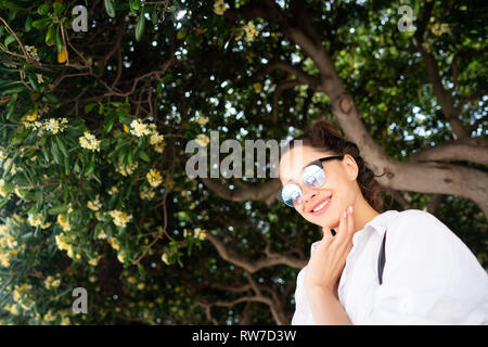 Belle jeune fille posant sur l'arrière-plan d'arbre à feuilles persistantes Banque D'Images