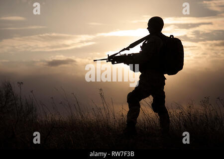 Silhouette of U.S. Marine au fusil contre le coucher du soleil. Banque D'Images