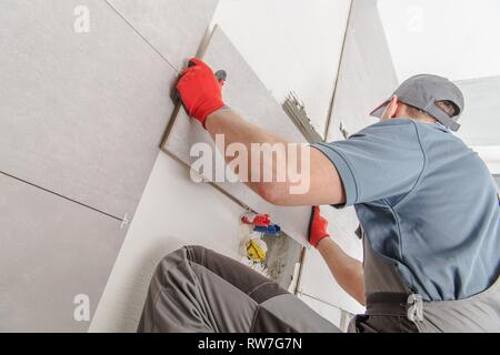 Portrait d'installation de carreaux de céramique dans la trentaine créer tout nouveau mur de carreaux Grand Format moderne à l'intérieur des bains. Remodelage professionnel Banque D'Images