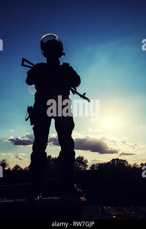 Silhouette d'agent de police avec des armes au coucher du soleil. Banque D'Images