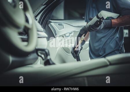 Voiture de service professionnel à l'aspirateur. Travailleur avec Qualité du commerce vide dans les mains. Nettoyer l'intérieur du véhicule de maintien. Banque D'Images