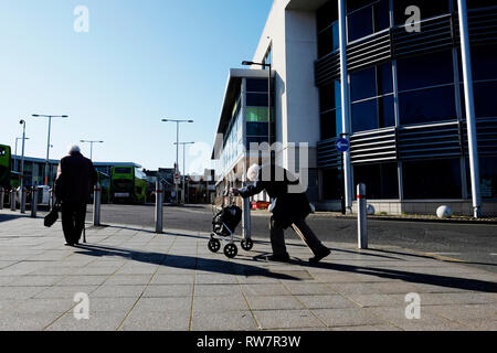 Un vieil homme, se baissa, pousse son panier en amont dans la station centrale d'autobus à Newport, île de Wight, au Royaume-Uni. Banque D'Images