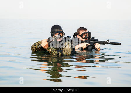 Plongeurs de Navy SEAL avec équipement de plongée complet et d'armes dans l'eau. Banque D'Images