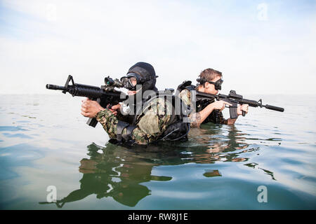 Plongeurs de Navy SEAL avec équipement de plongée complet et d'armes dans l'eau. Banque D'Images