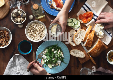 Couple manger de délicieux et sain petit-déjeuner ou déjeuner vue d'en haut. Des collations, apéritifs, salade de roquette, des sandwichs au jambon et légumes Banque D'Images