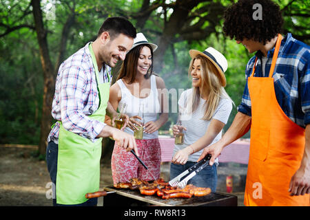 Groupe d'amis heureux de manger et boire des bières à dîner barbecue Banque D'Images