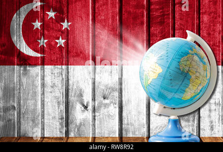 Globe avec une carte du monde sur un fond de bois avec l'image du drapeau de Singapour. La notion de voyage et de loisir à l'étranger. Banque D'Images