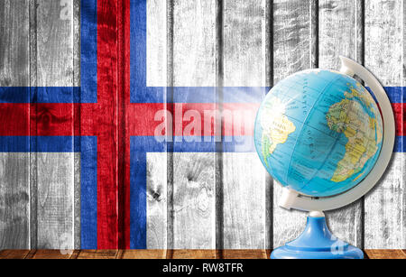 Globe avec une carte du monde sur un fond de bois avec l'image du drapeau d'Îles Féroé. La notion de voyage et de loisir à l'étranger. Banque D'Images