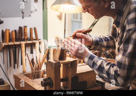 Sculpteur sur bois à un établi sculpter une figure en bois Banque D'Images