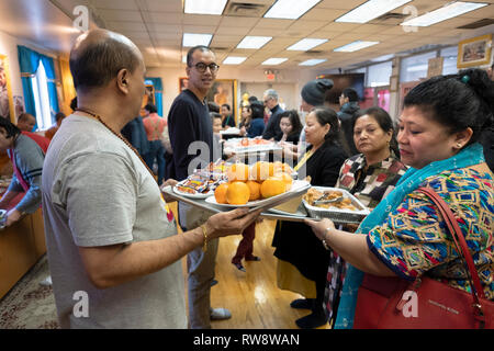 Fidèles à un temple bouddhiste forment une chaîne de montage d'offrir des aliments préparés et cuisinés pour leurs moines. Dans Elmhurst, Queens, New York Banque D'Images