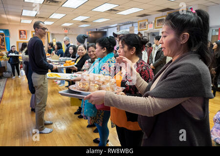 Fidèles à un temple bouddhiste forment une chaîne de montage d'offrir des aliments préparés et cuisinés pour leurs moines. Dans Elmhurst, Queens, New York Banque D'Images