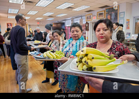 Fidèles à un temple bouddhiste forment une chaîne de montage d'offrir des aliments préparés et cuisinés pour leurs moines. Dans Elmhurst, Queens, New York Banque D'Images