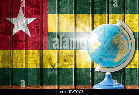 Globe avec une carte du monde sur un fond de bois avec l'image du drapeau du Togo. La notion de voyage et de loisir à l'étranger. Banque D'Images