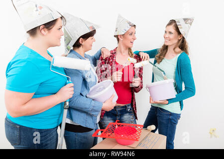 Female friends holding paint bucket, pinceau et rouleau Banque D'Images