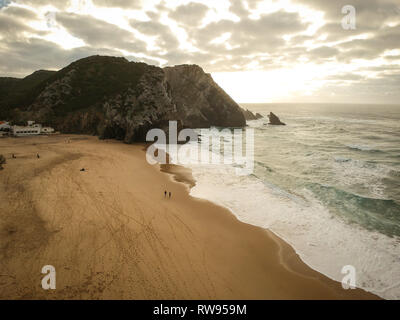 Vue aérienne d'une plage de sable au coucher du soleil avec une étonnante falaise. Plage Adraga Sintra, Portugal Banque D'Images