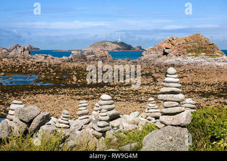 L'Île ronde et le phare du sceau de Porth, Saint Martin's, Îles Scilly, UK : cairns sculptés en pierre en premier plan Banque D'Images