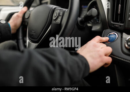 Moteur de voiture pilote en poussant le bouton start-stop en voiture moderne. Banque D'Images