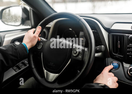 Moteur de voiture pilote en poussant le bouton start-stop en voiture moderne. Banque D'Images