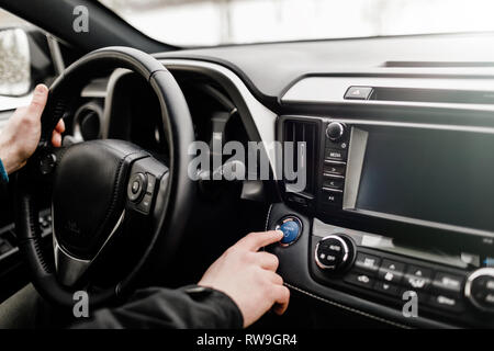 Moteur de voiture pilote en poussant le bouton start-stop en voiture moderne. Banque D'Images