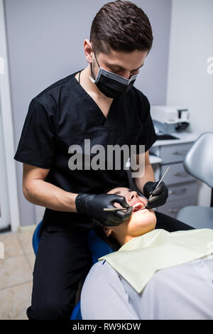 Dentiste examine les dents du patient sur le fauteuil du dentiste Banque D'Images