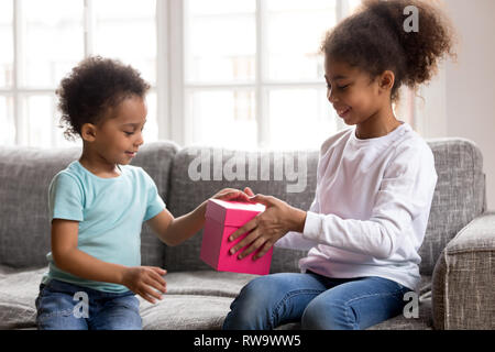 Prendre soin African American girl présent boîte-cadeau à petit frère Banque D'Images