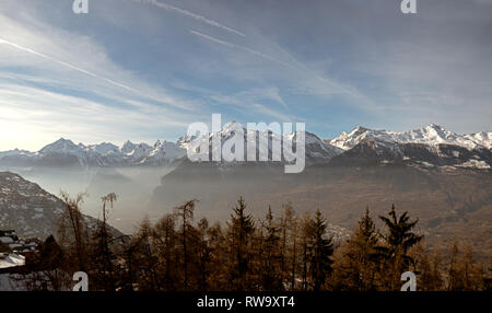 Couvert de neige et les pics de haute montagne et de l'alpin misty Valley de la région du Valais Suisse. Banque D'Images