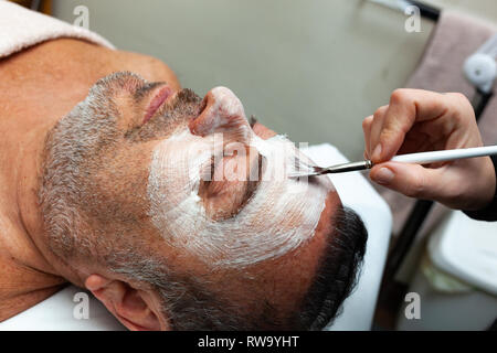 Homme d'âge moyen dans un salon de beauté avec un masque facial. Banque D'Images