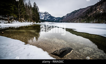 L'épaisseur de la glace sur le lac gelé à Vorderer Langbathsee. De belles montagnes aux sommets enneigés reflètent dans le crystal clear lake Banque D'Images