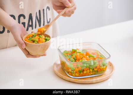 Louche de jeunes légumes fraîchement récoltés à la vapeur y compris les carottes, en Coupe ondulée, de pois et de pommes de terre pour un accompagnement sain pour le dîner Banque D'Images