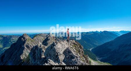 Randonneur se dresse sur les rochers à la recherche dans la distance, sentier de randonnée pédestre sur le Hochvogel, vue à partir de la selle à l'Kreuzspitze sur Banque D'Images