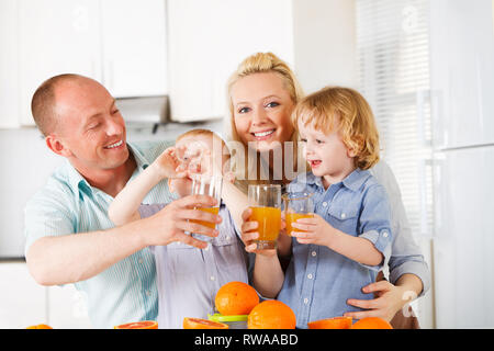 Famille heureuse c'est boire du jus d'orange sur leur cuisine Banque D'Images