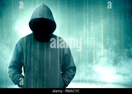 Hacker en noir hoodie debout avec un code binaire sur un écran virtuel sur fond vert Banque D'Images
