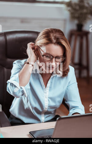 Blonde mature woman wearing glasses working on laptop Banque D'Images
