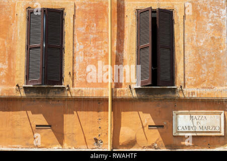 Ouvrir ses volets aux fenêtres dans un mur vieilli à Rome, Italie. Banque D'Images