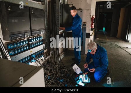 Les électriciens sont la réparation d'un standard téléphonique dans un sous-sol. Banque D'Images