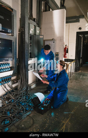 Les électriciens sont la réparation d'un standard téléphonique dans un sous-sol. Banque D'Images