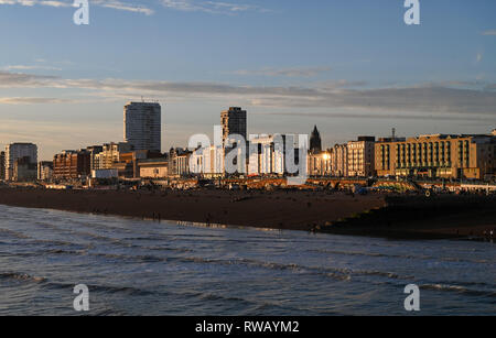 Vue sur le front de mer de Brighton et de la plage au coucher du soleil avec soleil qui brille sur les bâtiments de mer emblématique Banque D'Images