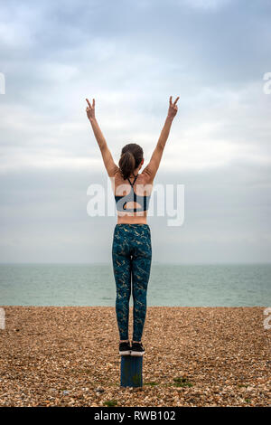 Femme debout avec les bras levés, sur la plage, vue de dos, copyspace Banque D'Images