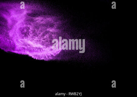 Explosion de poussière pourpre sur fond noir. La poussière de poudre de couleur aux éclaboussures. Banque D'Images