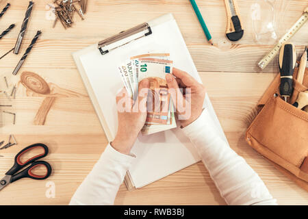 Female carpenter comptant de l'argent, vue de dessus de l'Union Européenne Euro mains tenant du papier-monnaie Banque D'Images