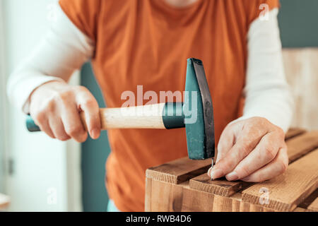 Female carpenter hammering nail dans des caisses en bois dans la petite entreprise de l'atelier de menuiserie, selective focus Banque D'Images