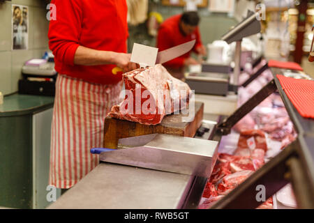 Butcher vend la viande de boeuf haché dans un marché Banque D'Images