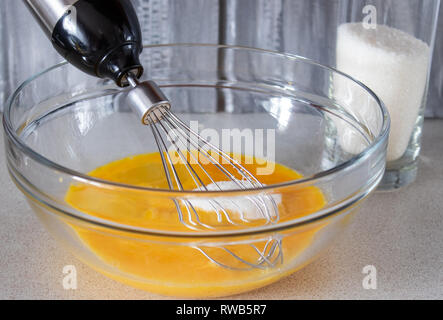 Zbitye oeufs dans un bol en verre avec du sucre sur la table. Banque D'Images