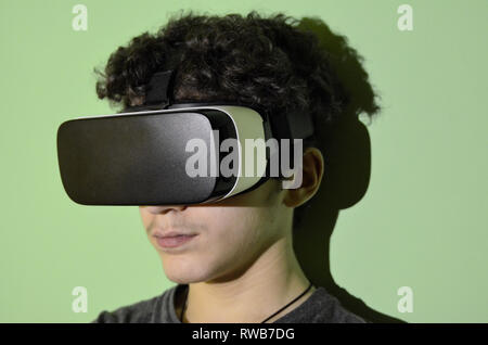 Un jeune garçon de race blanche porte le VR 360 événements dans sa chambre, l'expérience de réalité virtuelle reflète dans ses grimaces. Banque D'Images