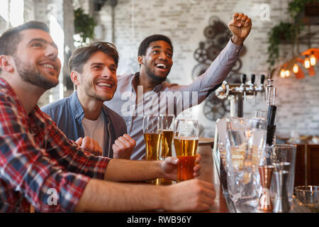 Les amis regarder le football et célébrer la victoire dans le sport bar Banque D'Images