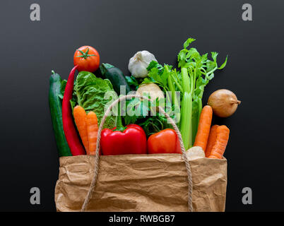 Les légumes frais biologiques en sac en papier brun contre l'arrière-plan du tableau sombre Banque D'Images